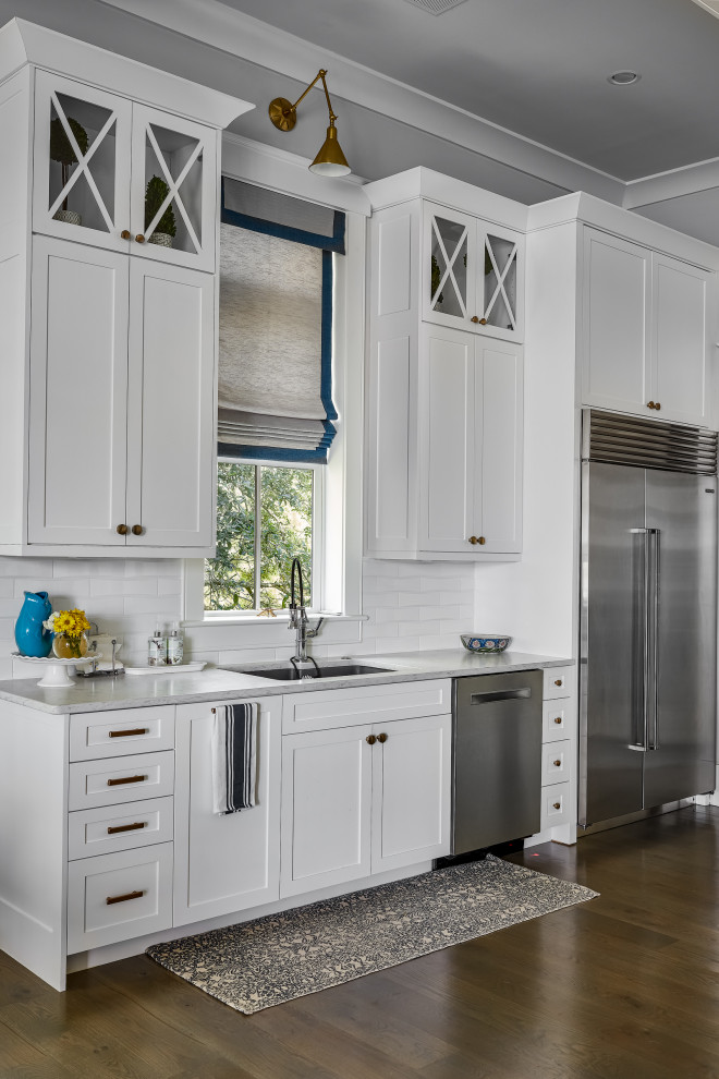 Large nautical galley kitchen/diner in Charleston with a submerged sink, white cabinets, metro tiled splashback, stainless steel appliances, brown floors, white worktops and white splashback.