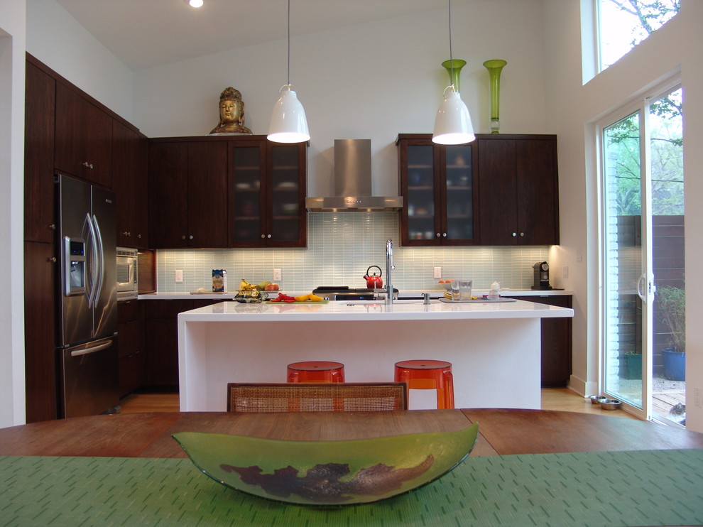 Foto di una cucina design con paraspruzzi con piastrelle di vetro, elettrodomestici in acciaio inossidabile, paraspruzzi bianco e ante in legno bruno