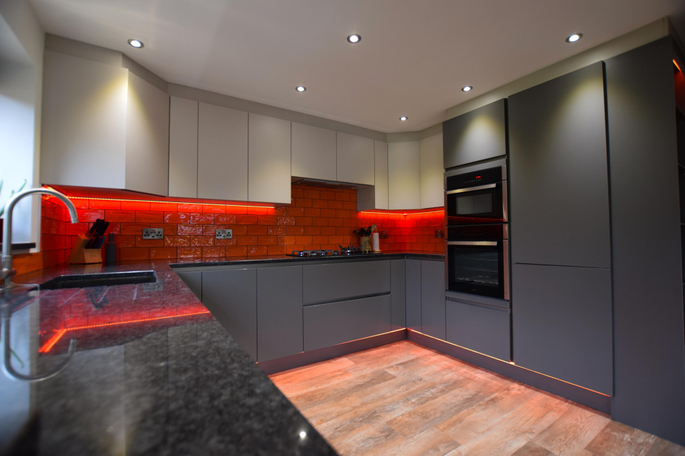 Design ideas for a medium sized contemporary u-shaped kitchen in Other with a submerged sink, flat-panel cabinets, grey cabinets, red splashback, metro tiled splashback, no island, brown floors and black worktops.