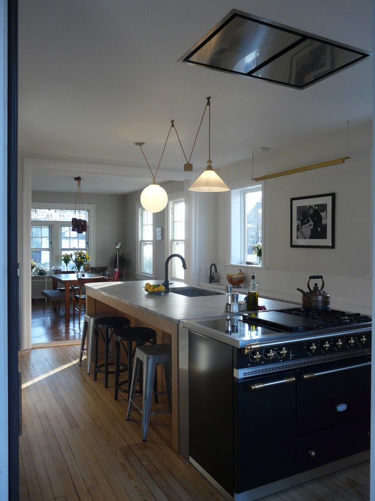Idéer för att renovera ett mellanstort vintage grå grått kök och matrum, med en undermonterad diskho, släta luckor, skåp i ljust trä, granitbänkskiva, vitt stänkskydd, rostfria vitvaror, mellanmörkt trägolv och en köksö