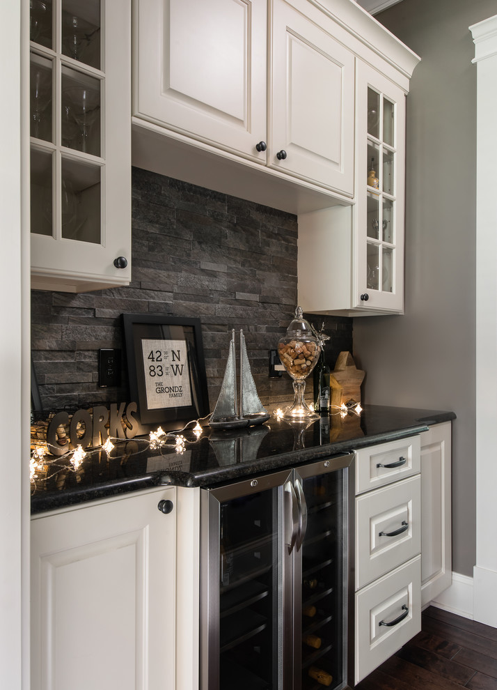 This is an example of a traditional open plan kitchen in Detroit with a submerged sink, raised-panel cabinets, white cabinets, granite worktops, grey splashback, stone tiled splashback, stainless steel appliances, dark hardwood flooring and an island.