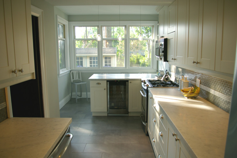 Inspiration for a mid-sized transitional galley slate floor eat-in kitchen remodel in Toronto with an undermount sink, shaker cabinets, white cabinets, marble countertops, beige backsplash, glass tile backsplash, stainless steel appliances and a peninsula