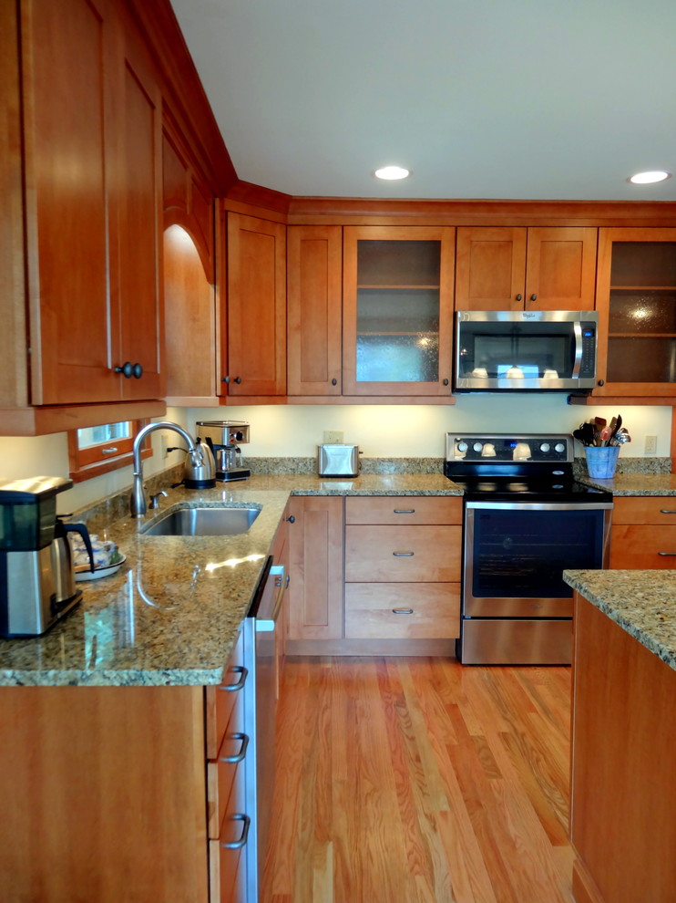 Example of a mid-sized trendy l-shaped medium tone wood floor eat-in kitchen design in Charlotte with an undermount sink, recessed-panel cabinets, medium tone wood cabinets, granite countertops, beige backsplash, stainless steel appliances and an island