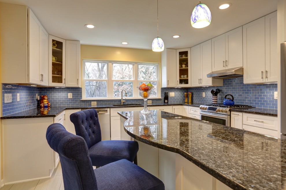 Esempio di una cucina design con lavello integrato, ante con riquadro incassato, ante bianche, top in granito, paraspruzzi blu, paraspruzzi con piastrelle di vetro, elettrodomestici in acciaio inossidabile e pavimento in travertino