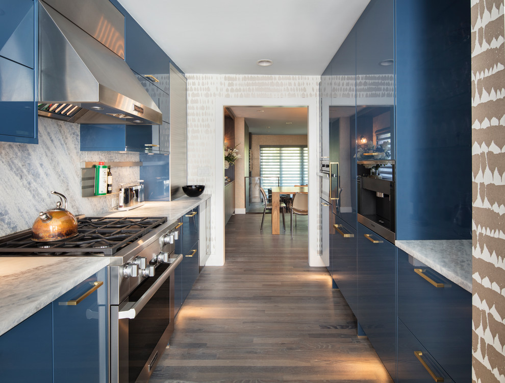 Стильный дизайн: параллельная кухня в современном стиле с плоскими фасадами, синими фасадами, техникой из нержавеющей стали, паркетным полом среднего тона и обоями на стенах без острова - последний тренд