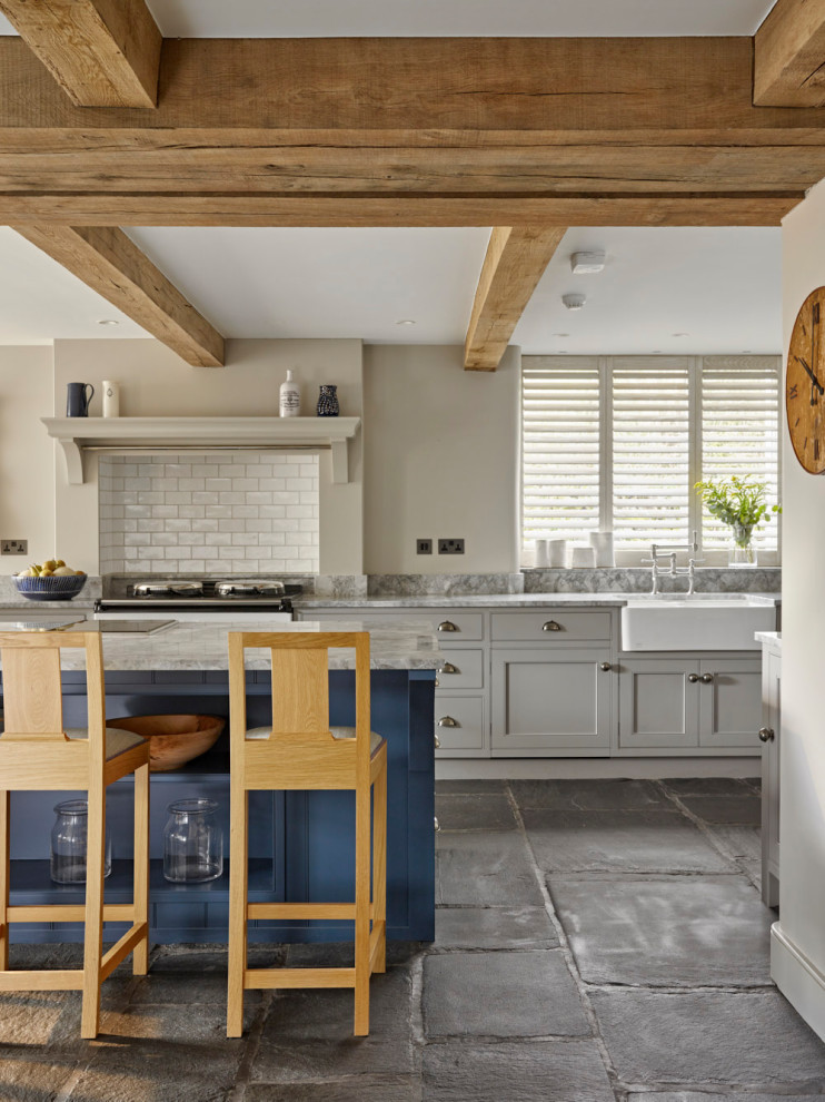 This is an example of a large rural kitchen/diner in Other with a belfast sink, beaded cabinets, grey cabinets, white splashback, ceramic splashback, stainless steel appliances, an island, grey floors, grey worktops and exposed beams.