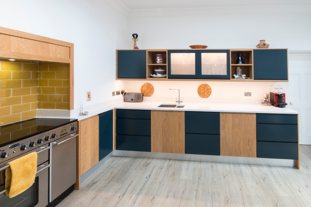 Modern inredning av ett mellanstort kök, med släta luckor, blå skåp, bänkskiva i kvartsit, vitt stänkskydd och laminatgolv