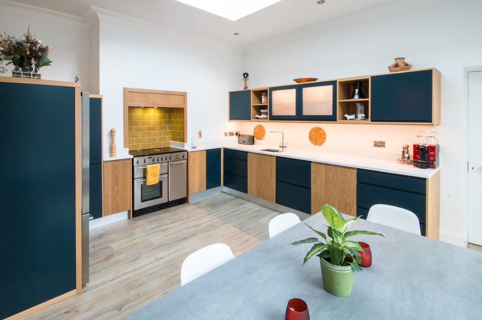 Inspiration for a mid-sized contemporary u-shaped laminate floor eat-in kitchen remodel in Dublin with flat-panel cabinets, blue cabinets, quartzite countertops, yellow backsplash and stainless steel appliances