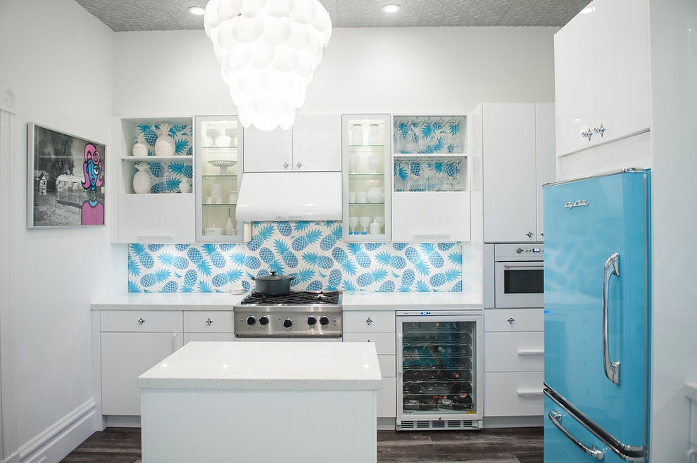 На фото: угловая кухня в современном стиле с плоскими фасадами, белыми фасадами, синим фартуком, цветной техникой и островом с