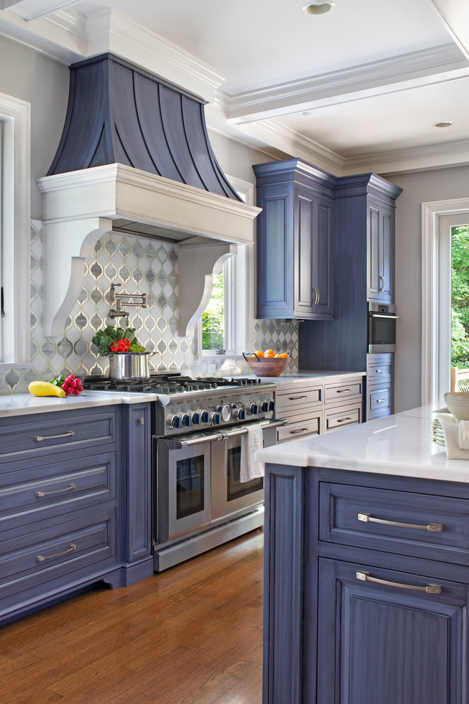 Bild på ett stort eklektiskt vit vitt kök, med en rustik diskho, luckor med profilerade fronter, blå skåp, bänkskiva i kvarts, vitt stänkskydd, glaspanel som stänkskydd, rostfria vitvaror, mellanmörkt trägolv, flera köksöar och brunt golv