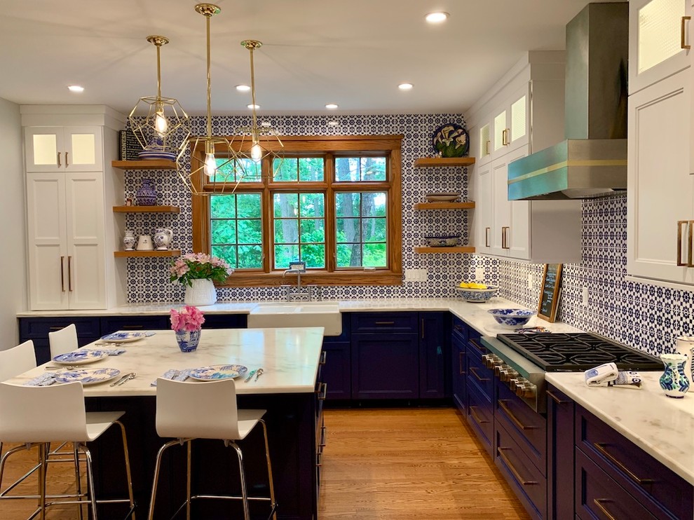 Example of a mid-sized classic u-shaped medium tone wood floor open concept kitchen design in Milwaukee with a farmhouse sink, recessed-panel cabinets, blue cabinets, marble countertops, multicolored backsplash, terra-cotta backsplash, paneled appliances, an island and white countertops