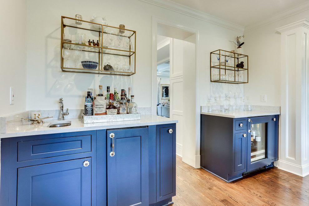 Photo of a large traditional home bar in DC Metro with beaded cabinets, engineered stone countertops and medium hardwood flooring.