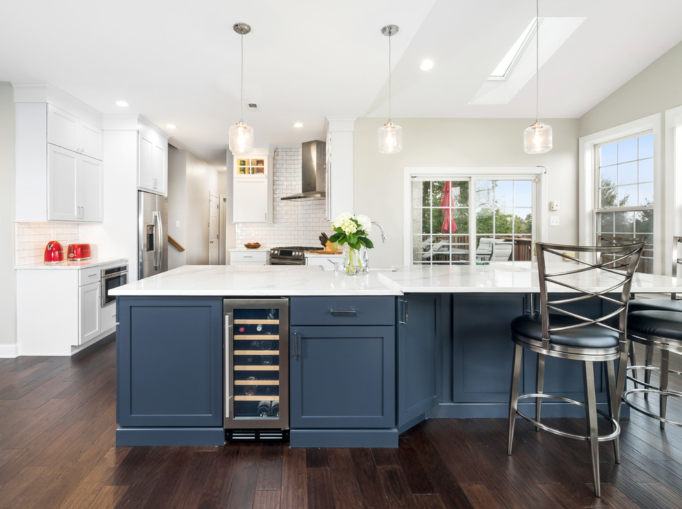 Eat-in kitchen - large transitional l-shaped dark wood floor and brown floor eat-in kitchen idea in Philadelphia with a farmhouse sink, shaker cabinets, white cabinets, quartz countertops, white backsplash, subway tile backsplash, stainless steel appliances, an island and blue countertops