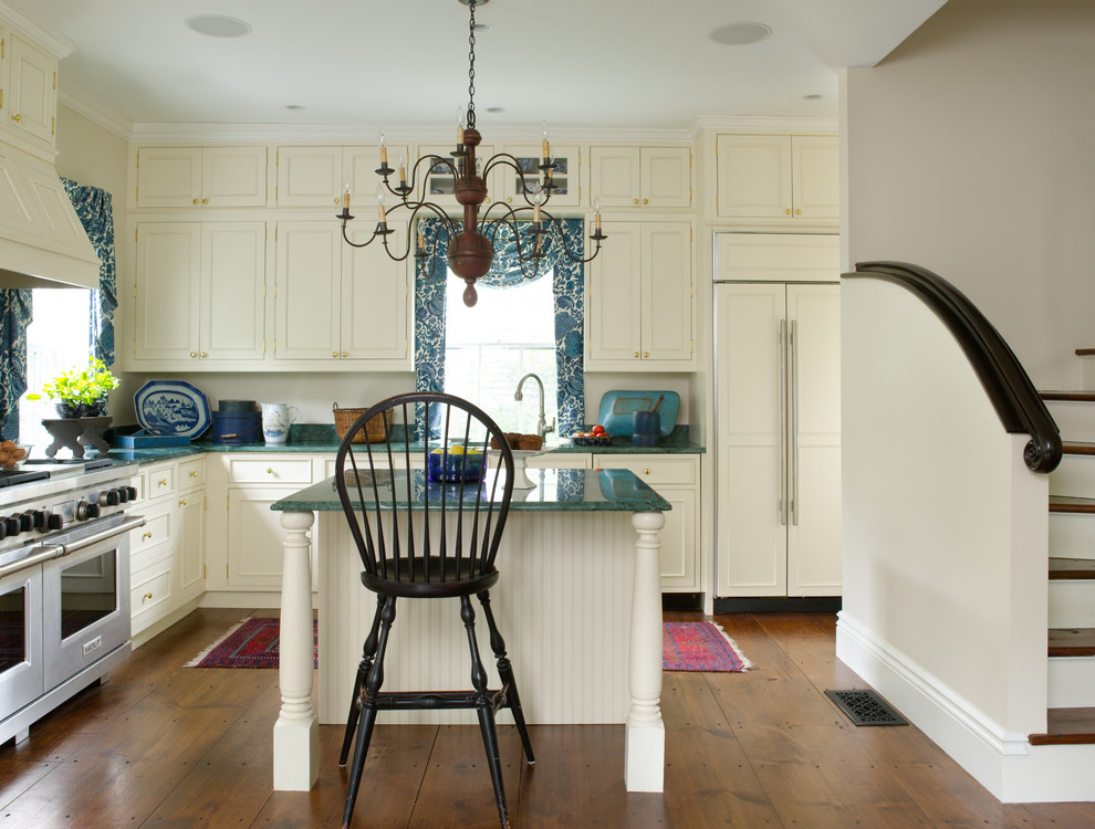 Klassische Küche in L-Form mit Kassettenfronten, beigen Schränken, Küchengeräten aus Edelstahl, braunem Holzboden, Kücheninsel, Granit-Arbeitsplatte und türkiser Arbeitsplatte in Boston