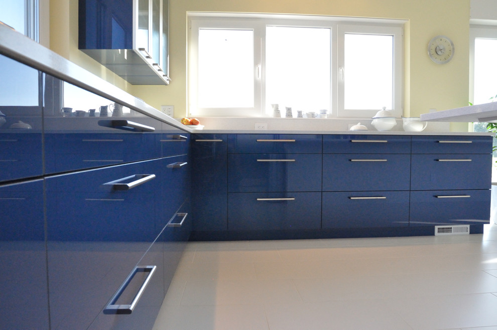 Cette photo montre une grande cuisine américaine moderne avec un placard à porte plane, des portes de placard bleues et îlot.