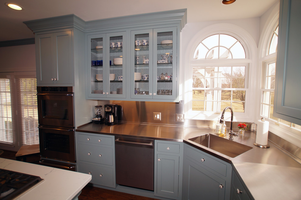 Foto di una cucina chic di medie dimensioni con ante blu, elettrodomestici in acciaio inossidabile, pavimento in legno massello medio, ante con riquadro incassato e top in quarzite
