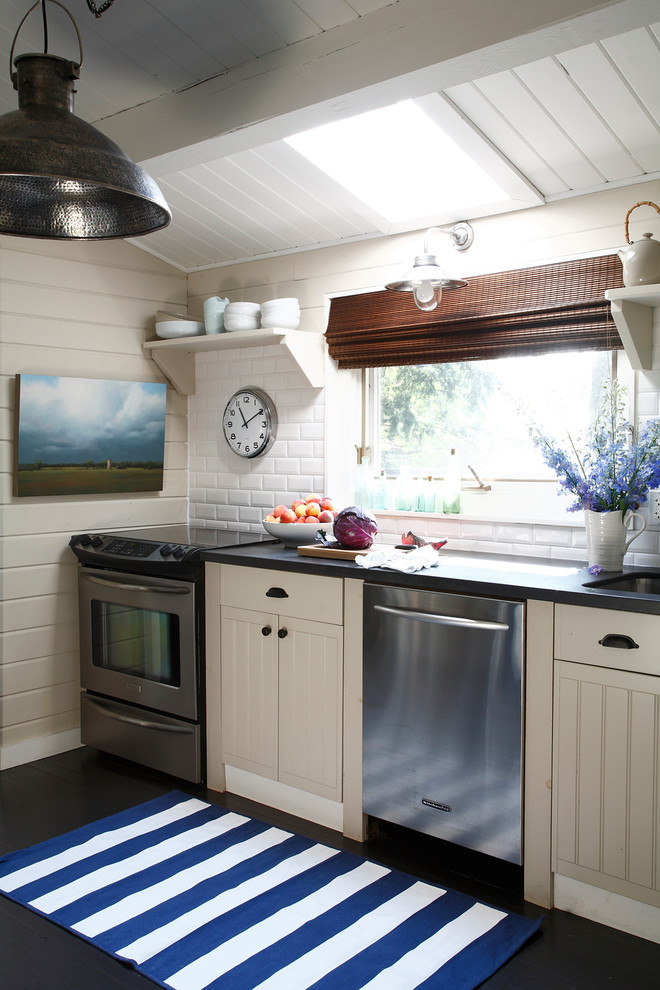 Photo of a beach style kitchen in Other with a submerged sink, white cabinets, white splashback, metro tiled splashback and stainless steel appliances.