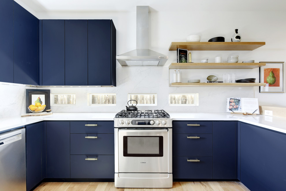 Nautical u-shaped kitchen in Austin with flat-panel cabinets, blue cabinets, white splashback, stainless steel appliances, light hardwood flooring and white worktops.