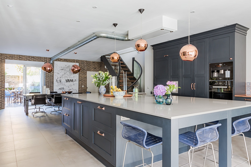 ロンドンにある高級な広いインダストリアルスタイルのおしゃれなキッチン (シェーカースタイル扉のキャビネット、青いキャビネット、黒い調理設備、グレーの床) の写真