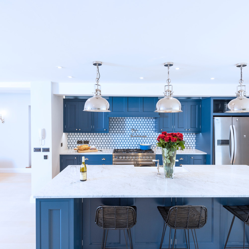 Foto di una grande cucina moderna con lavello stile country, ante con riquadro incassato, ante blu, top in marmo, paraspruzzi blu, elettrodomestici in acciaio inossidabile, parquet chiaro, pavimento beige e top beige