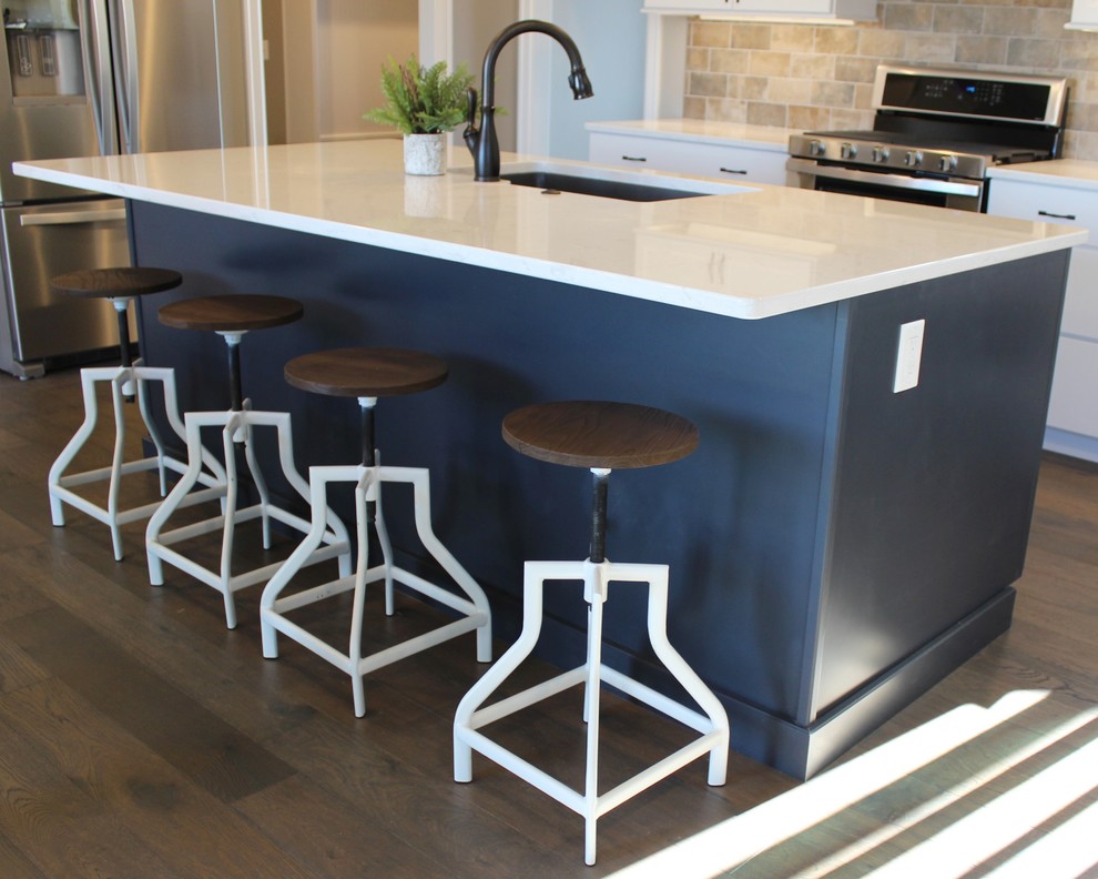 Example of a large danish l-shaped medium tone wood floor and gray floor open concept kitchen design in Other with an undermount sink, flat-panel cabinets, blue cabinets, quartz countertops, beige backsplash, porcelain backsplash, stainless steel appliances, an island and white countertops