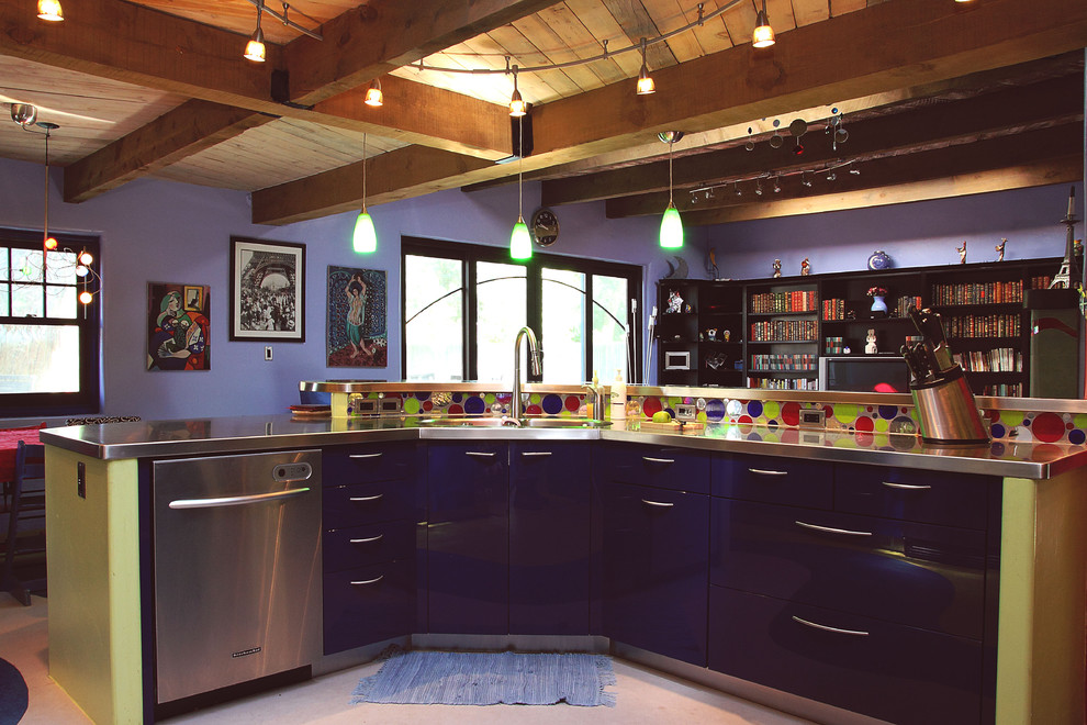 This is an example of an eclectic kitchen in Albuquerque with a built-in sink, flat-panel cabinets, blue cabinets, stainless steel worktops, yellow splashback, glass tiled splashback, stainless steel appliances, lino flooring and an island.