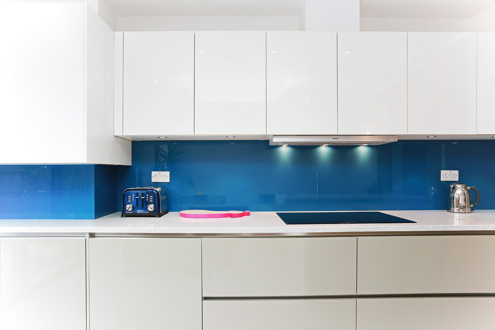 Foto de cocina contemporánea de tamaño medio con salpicadero azul, salpicadero de vidrio templado y una isla