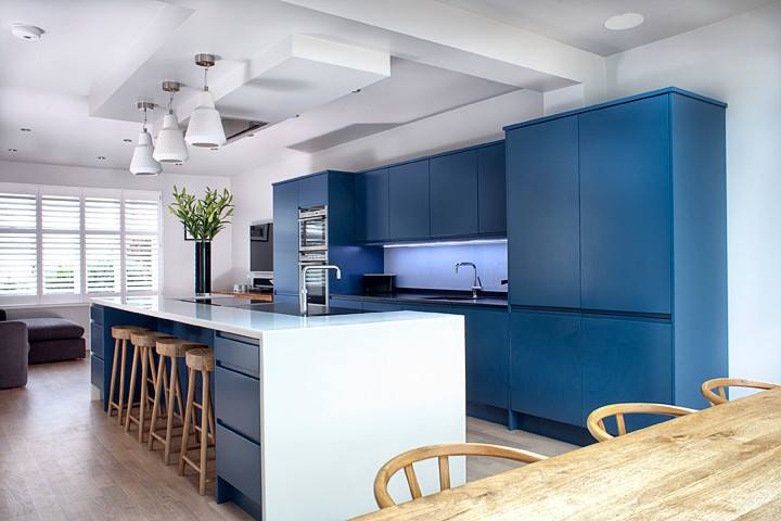 Photo of a medium sized modern galley kitchen/diner in Essex with a single-bowl sink, flat-panel cabinets, blue cabinets, stainless steel appliances and an island.