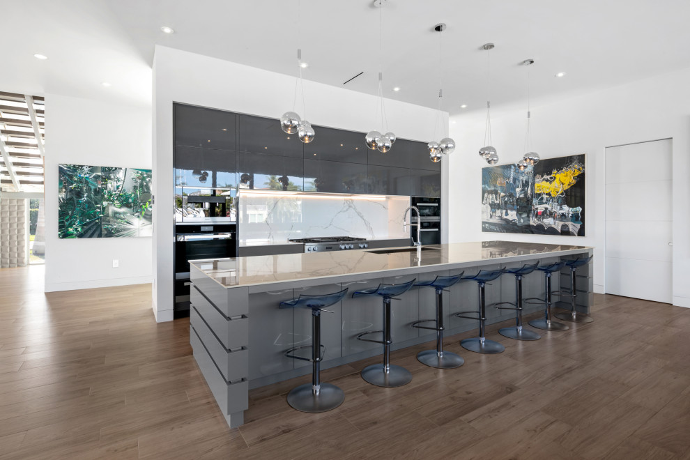Large modern single-wall open plan kitchen in Tampa with a submerged sink, flat-panel cabinets, grey cabinets, white splashback, porcelain splashback, black appliances, porcelain flooring, an island, brown floors and white worktops.