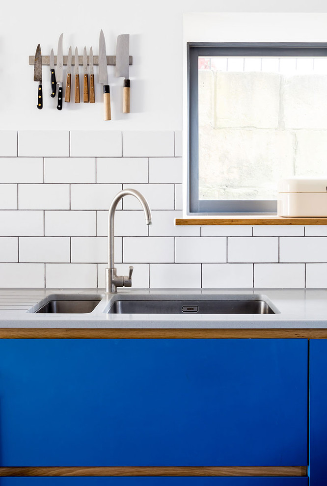 Inspiration for a medium sized contemporary u-shaped kitchen/diner in Wiltshire with a submerged sink, flat-panel cabinets, blue cabinets, white splashback, stone tiled splashback, stainless steel appliances, concrete flooring and no island.
