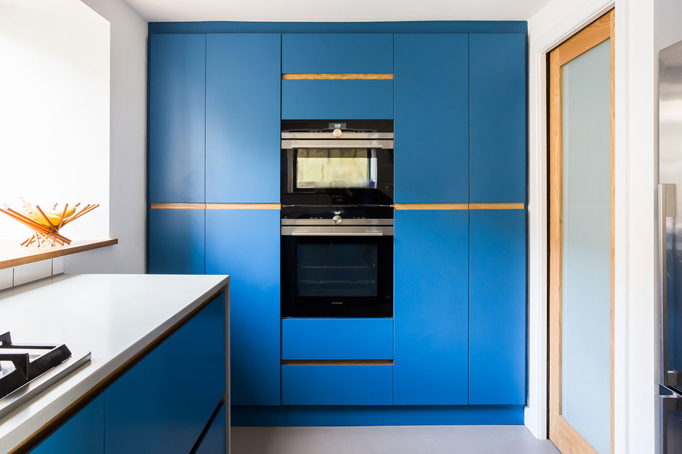 Design ideas for a medium sized contemporary u-shaped kitchen/diner in Wiltshire with a submerged sink, flat-panel cabinets, blue cabinets, white splashback, stone tiled splashback, stainless steel appliances, concrete flooring and no island.