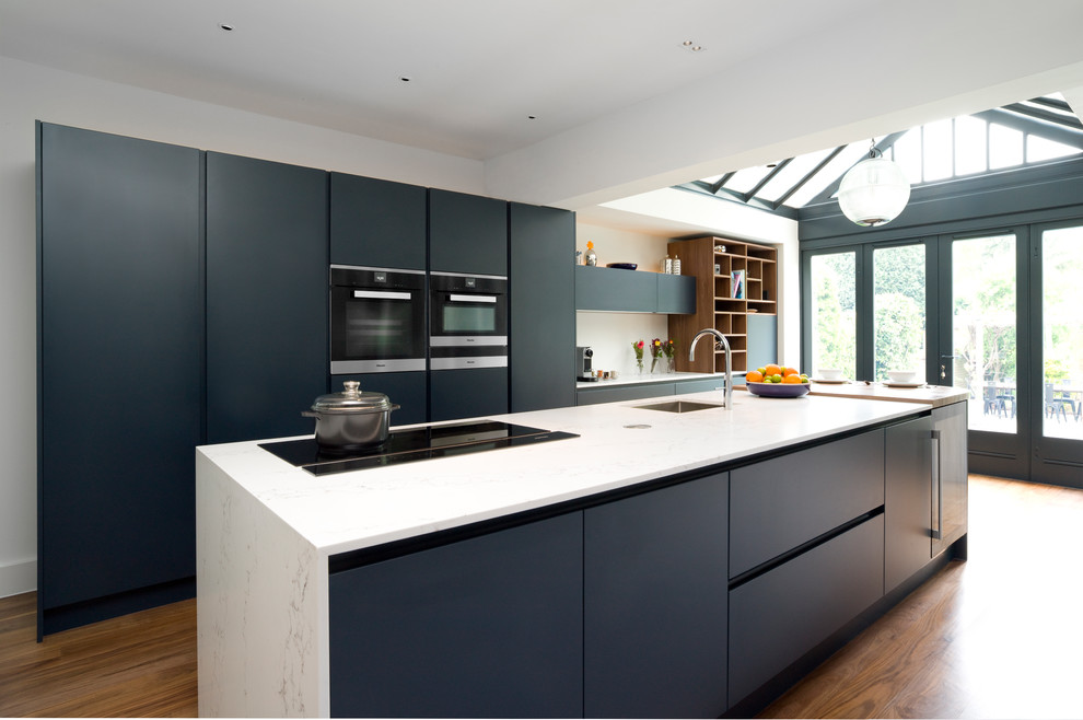 Foto di una grande cucina contemporanea con lavello sottopiano, ante lisce, ante blu, top in quarzite, elettrodomestici neri, parquet scuro e pavimento marrone