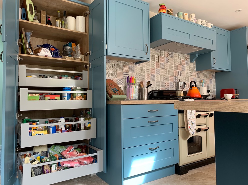 Design ideas for a medium sized eclectic l-shaped kitchen/diner in Buckinghamshire with shaker cabinets, blue cabinets, laminate countertops, multi-coloured splashback, ceramic splashback, travertine flooring and an island.