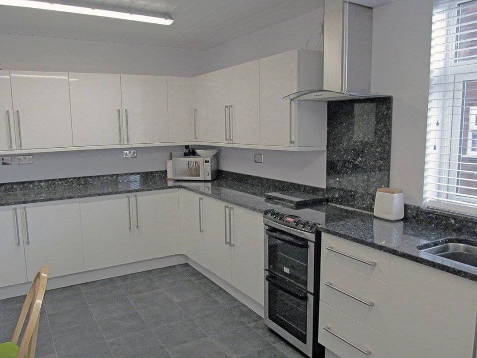 Moderne Küche in L-Form mit Unterbauwaschbecken, weißen Schränken, Granit-Arbeitsplatte, Küchenrückwand in Blau, bunten Elektrogeräten und blauer Arbeitsplatte in West Midlands