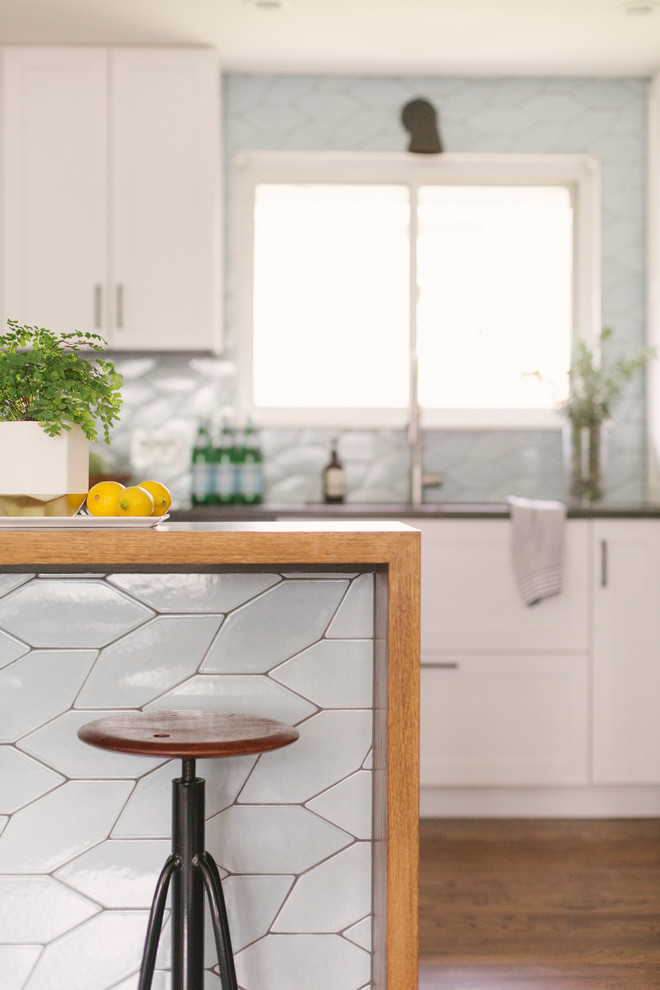Bild på ett mellanstort vintage grå linjärt grått kök och matrum, med vita skåp, blått stänkskydd, stänkskydd i keramik, rostfria vitvaror, mellanmörkt trägolv, en köksö och brunt golv
