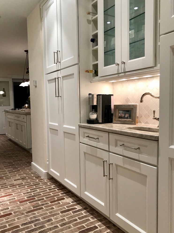 Photo of a kitchen in New York with a belfast sink, recessed-panel cabinets, white cabinets, quartz worktops, brick flooring and an island.