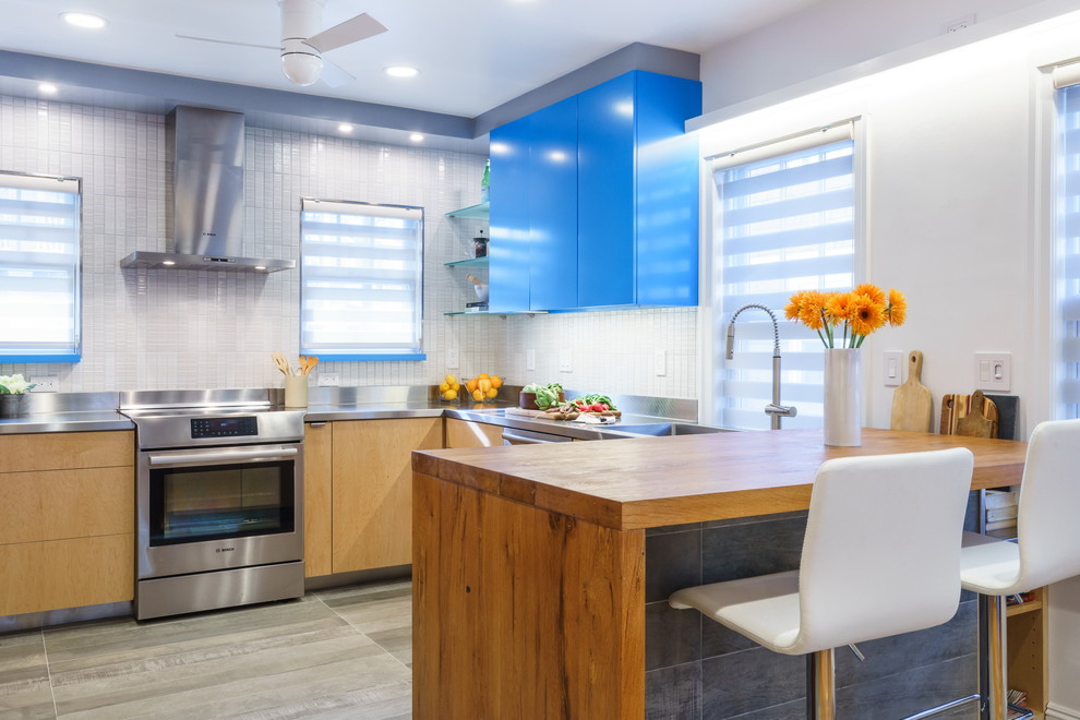 Mid-sized minimalist u-shaped porcelain tile eat-in kitchen photo in Boston with an island, an integrated sink, flat-panel cabinets, light wood cabinets, wood countertops, metallic backsplash, ceramic backsplash and stainless steel appliances