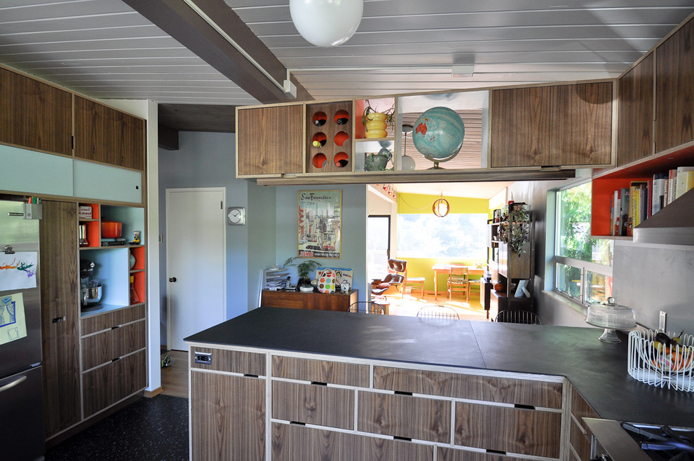 Ejemplo de cocina moderna con armarios con paneles lisos, puertas de armario de madera oscura y electrodomésticos de acero inoxidable