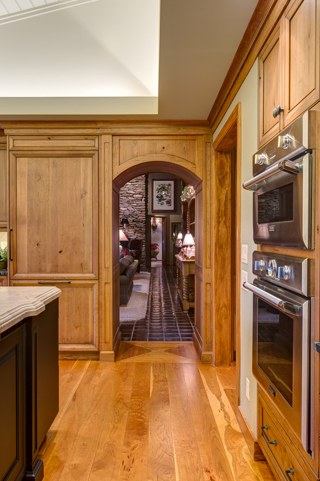 Exempel på ett stort klassiskt kök, med luckor med infälld panel, skåp i mellenmörkt trä, granitbänkskiva, rostfria vitvaror, mellanmörkt trägolv och en köksö