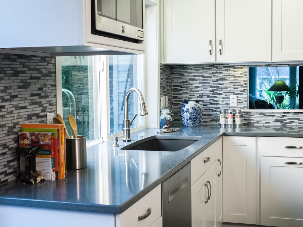 Foto på ett mellanstort funkis kök, med en dubbel diskho, skåp i shakerstil, vita skåp, granitbänkskiva, flerfärgad stänkskydd, stänkskydd i glaskakel, rostfria vitvaror, en köksö, vinylgolv och brunt golv