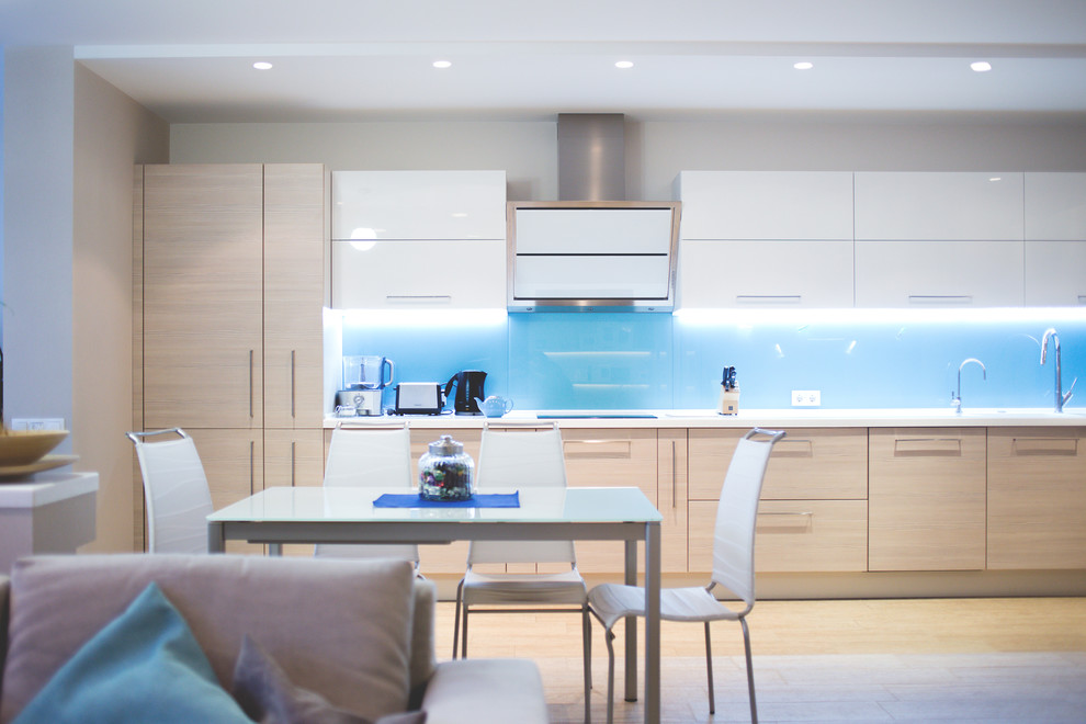Ejemplo de cocinas en L contemporánea grande abierta con fregadero integrado, salpicadero azul, salpicadero de vidrio templado y suelo de baldosas de cerámica