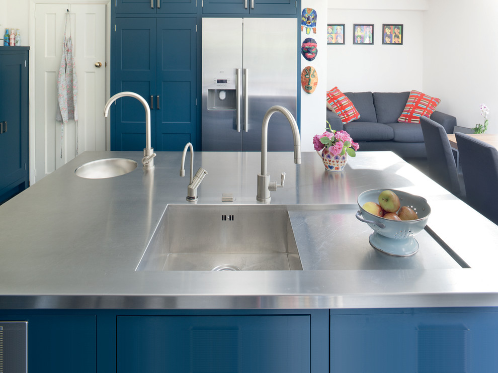 Ispirazione per una cucina contemporanea di medie dimensioni con lavello integrato, ante in stile shaker, ante blu, top in legno, paraspruzzi a effetto metallico, elettrodomestici in acciaio inossidabile e pavimento in ardesia