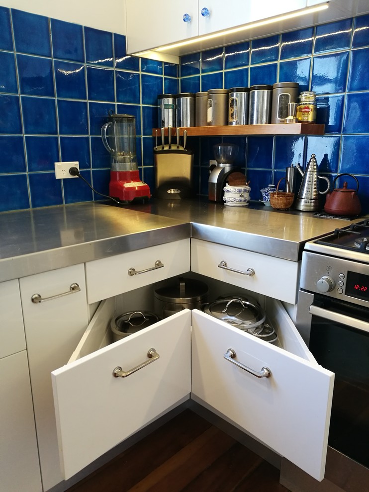 Idéer för mellanstora kök, med släta luckor, vita skåp, bänkskiva i rostfritt stål, blått stänkskydd, stänkskydd i keramik, rostfria vitvaror, mellanmörkt trägolv och brunt golv