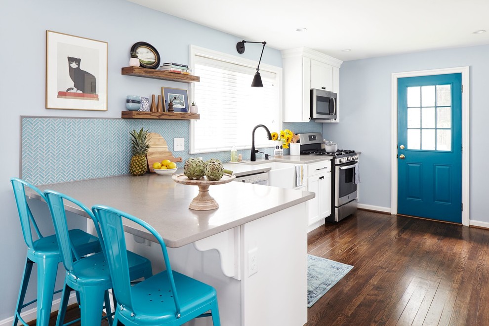 Bild på ett vintage grå grått kök, med en rustik diskho, luckor med infälld panel, vita skåp, blått stänkskydd, rostfria vitvaror, mörkt trägolv, en halv köksö och brunt golv