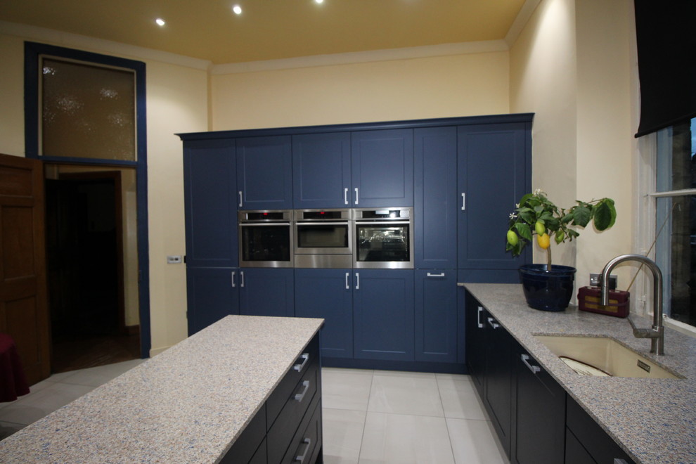 Mittelgroße Moderne Wohnküche mit integriertem Waschbecken, blauen Schränken, Küchengeräten aus Edelstahl, Porzellan-Bodenfliesen und Kücheninsel in Glasgow