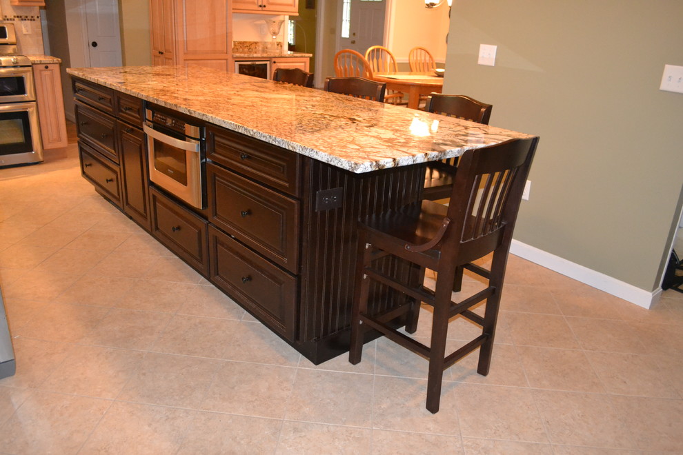 Example of a mid-sized classic l-shaped porcelain tile eat-in kitchen design in Boston with an undermount sink, raised-panel cabinets, light wood cabinets, granite countertops, beige backsplash, porcelain backsplash, stainless steel appliances and an island