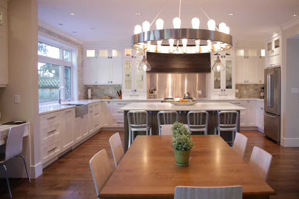 Elegant u-shaped eat-in kitchen photo in Vancouver with an undermount sink, shaker cabinets, white cabinets, quartz countertops, beige backsplash, stone tile backsplash and stainless steel appliances