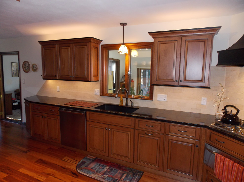 Example of a mid-sized trendy u-shaped medium tone wood floor eat-in kitchen design in Chicago with an undermount sink, raised-panel cabinets, medium tone wood cabinets, granite countertops, yellow backsplash, porcelain backsplash and stainless steel appliances