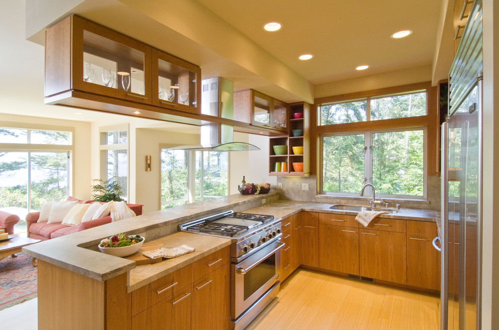 Photo of a classic u-shaped open plan kitchen in Seattle with a submerged sink, flat-panel cabinets, medium wood cabinets, granite worktops, beige splashback, stone slab splashback, stainless steel appliances and bamboo flooring.