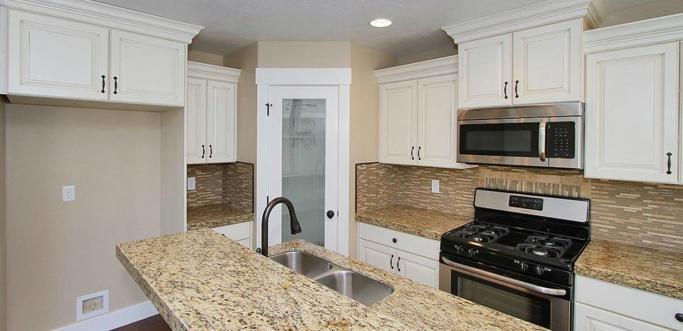 Amerikansk inredning av ett mellanstort kök, med en undermonterad diskho, luckor med upphöjd panel, vita skåp, granitbänkskiva, beige stänkskydd, glaspanel som stänkskydd, rostfria vitvaror, mellanmörkt trägolv och en köksö